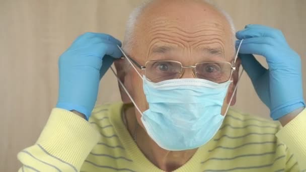 Pensionné met masque jetable bleu et fixe sur les oreilles — Video