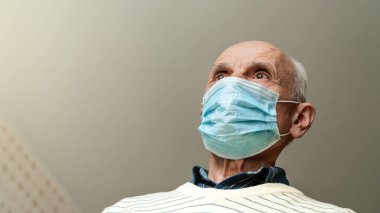 Maskeli kel emekli tavana karşı alçak açılı çekim yapıyor.