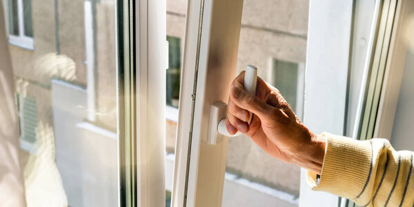 man hand holds plastic window handle to open vent closeup