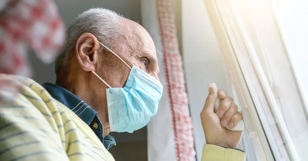 Yüz maskeli emekli, pencere kolunda el ele tutuşuyor.