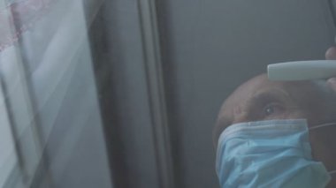 Maskeli üzgün emeklinin pencere koluna gelmesi