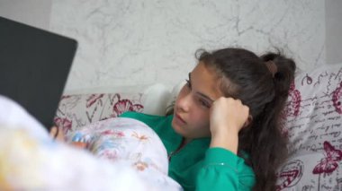 Uzun saçlı üzgün genç kız dizüstü bilgisayara bakıyor.