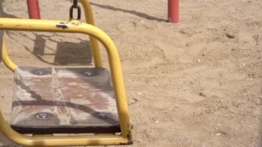 Kumların üzerinde kahverengi tahta dalgalarla eski sarı salıncak