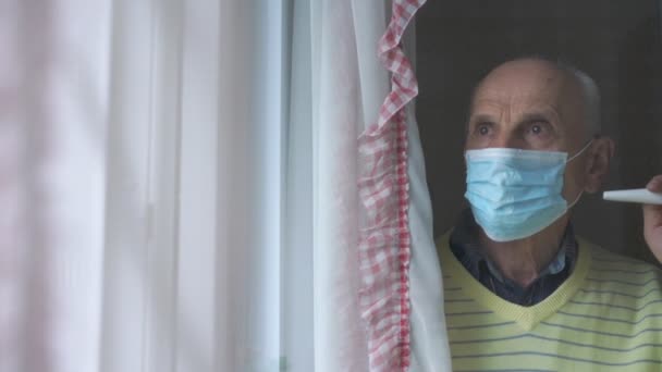 Alter Mann mit blauer Gesichtsmaske steht vor Plastikfenstern in Nahaufnahme — Stockvideo