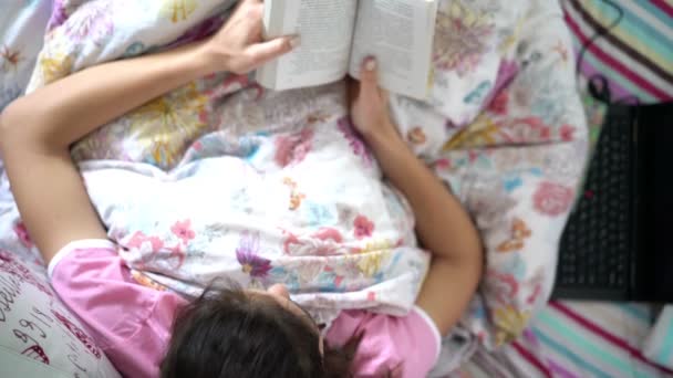 Adolescente chica se encuentra en cama lectura libro vista superior de la cabeza — Vídeos de Stock