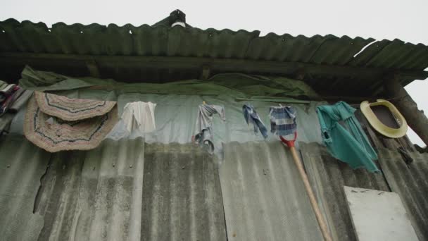 Verschiedene farbige Kleidungsstücke hängen unter grauem Dach in der Schlange — Stockvideo