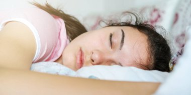 At kuyruklu genç kız yastıklarla yatakta uyuyor.