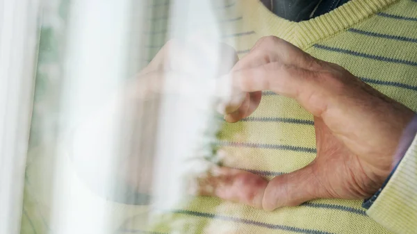 Mãos homem mostrar coração contra vestido amarelo na janela closeup — Fotografia de Stock
