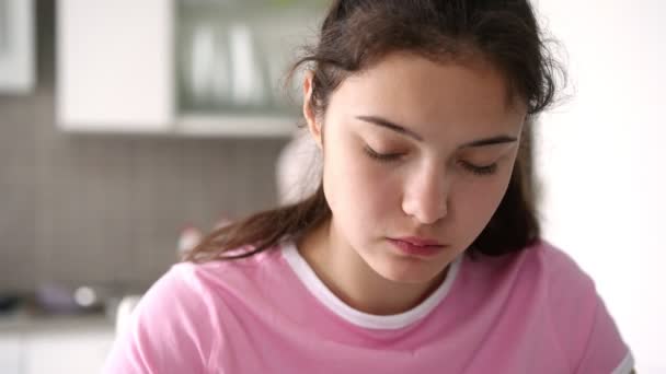 Девушка-подросток в фиолетовой футболке ест салат с огурцами — стоковое видео