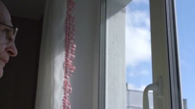 Emekli, renkli perdeleri ve beyaz plastik pencereleri açıyor