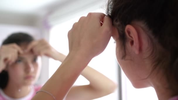 Teenagermädchen mit Pferdeschwanz knallt Zits reflektiert im Spiegel — Stockvideo