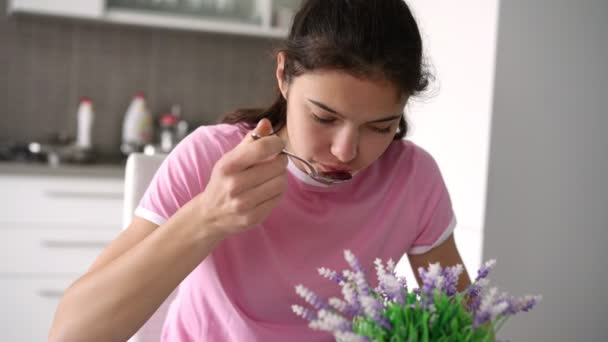 Tiener meisje met lang haar eet cornflakes voor ontbijt — Stockvideo