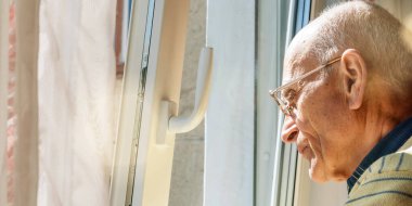 Kel yaşlı adam pencerenin önünde dikilip yakından bakıyor.