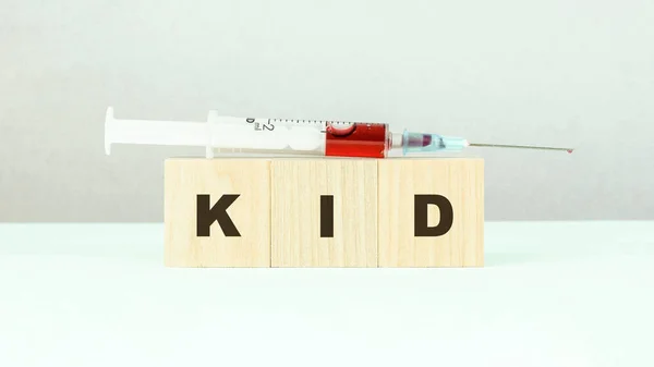 Palavra criança feita com blocos de madeira e seringa com vacina — Fotografia de Stock
