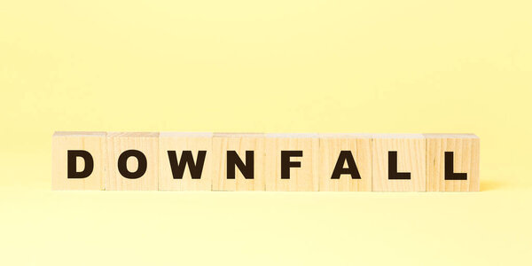word downfall with black letters on wooden cubes on yellow