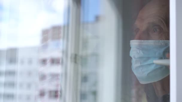 Hombre viejo borroso en la reflexión máscara azul en vidrio de la ventana — Vídeos de Stock