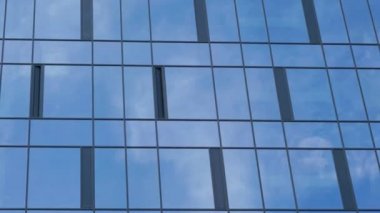 büyük pencereli ofis binası beyaz bulutları yansıtır
