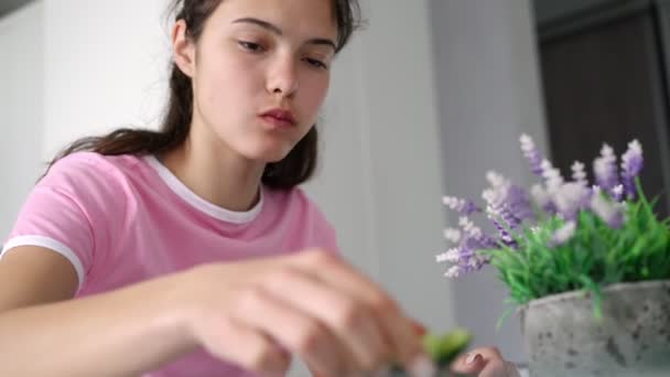 Ung kvinna med långt hår äter sallad vid bordet med lavendel — Stockvideo