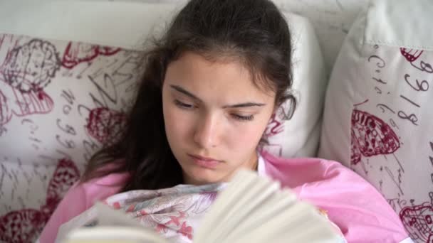 Mujer joven concentrada se encuentra en grandes almohadas en la cama — Vídeos de Stock