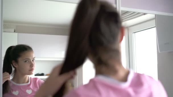 Uzun saçlı genç kız siyah saç fırçasıyla at kuyruğu tarıyor. — Stok video