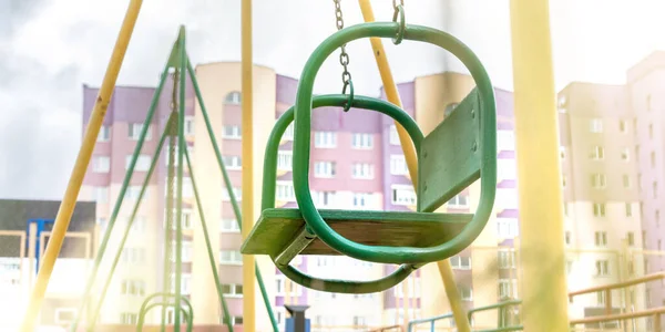 Зеленые качели висят на цепях рядом с детской площадкой — стоковое фото