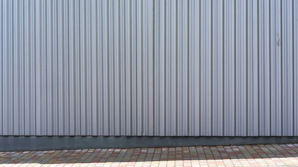 石舗装近くの灰色のリブ状の建物の壁 — ストック写真