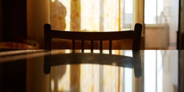 Tahta sandalye silueti pencerelere karşı masaya yansıtılıyor