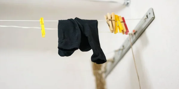 Schwarze Socken hängen an dünner Spitze neben farbigen Wäscheklammern — Stockfoto