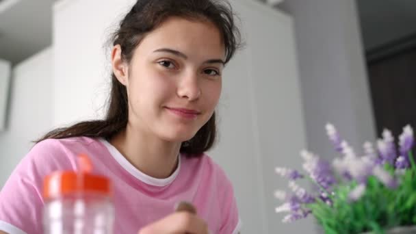 Colegiala tiene comida hablando y sonriendo en la mesa en la cocina — Vídeos de Stock