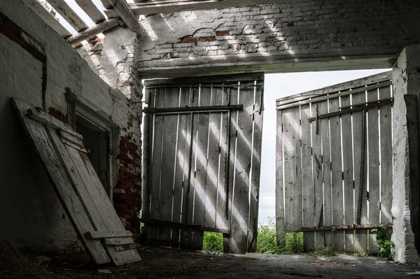 Güneş ışığı çatıdaki deliklerden yıkık bina kapısına düşüyor.