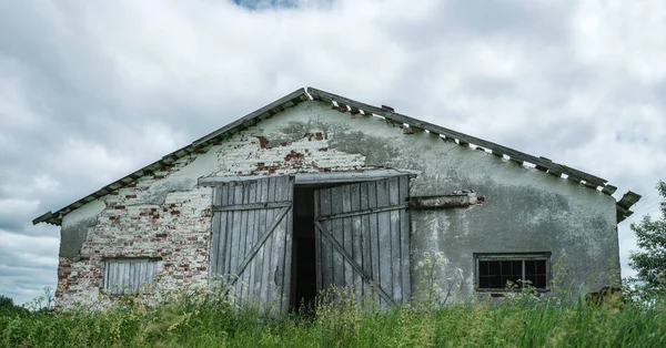 Bâtiment abandonné désuet de couleur grise avec porte en bois — Photo