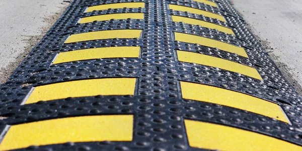 long black rubber speed bump with yellow stripes on road