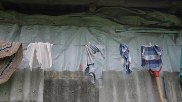 Olas de viento ropa de colores colgando de la cuerda bajo el techo gris — Vídeo de stock