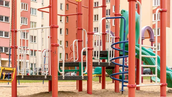 Rojo verde parque infantil atracciones en el patio contra la construcción — Foto de Stock