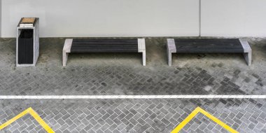 Beton destekli gri banklar ve çöp kutusu