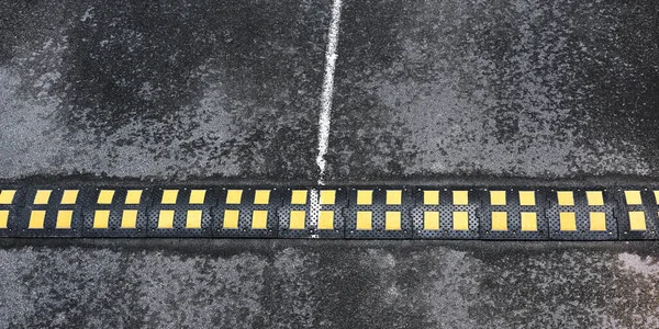Bosse de vitesse noire avec marquage jaune située sur l'asphalte — Photo