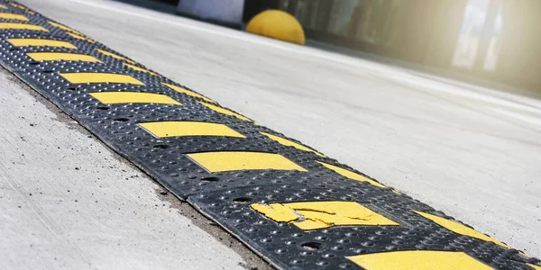 회색 도로에 위치 한 노란색 줄무늬가 있는 검정 스피드 범프 — 스톡 사진