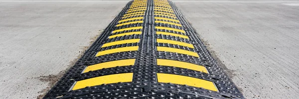 Bosse de vitesse en caoutchouc à rayures jaunes située sur asphalte — Photo