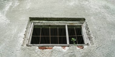 Gri duvarı ve tarihi geçmiş ahşap penceresi olan klasik bir bina.