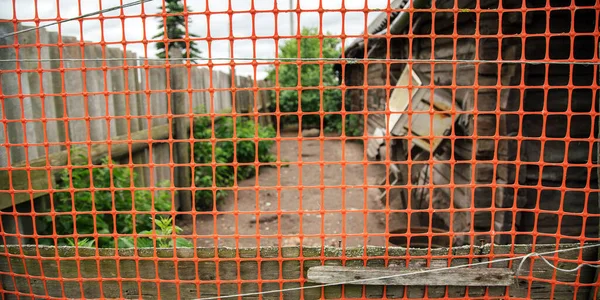 Útvonal udvarban között kerítés és régi ház mögött narancssárga rács — Stock Fotó
