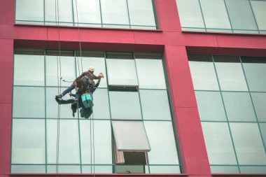 Temizlik işçisi gökdelen duvarındaki camları siliyor.