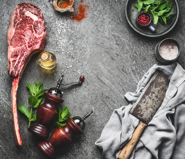 肉をきれいに生のトマホークビーフステーキ 暗い素朴なコンクリートテーブルの背景に調味料と新鮮なハーブ トップビュー テキストのための場所 肉ステーキの準備 — ストック写真