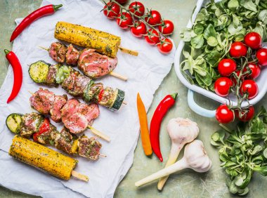 Sebzeli, mısır kulaklı ve soslu et şişleri, kırsal arka planda hazırlık, üst görünüm