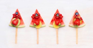 Beyaz ahşap arka planda meyveli ve meyveli buzlu karpuz dilimi. Sağlıklı gıda ve vejetaryen yeme konsepti