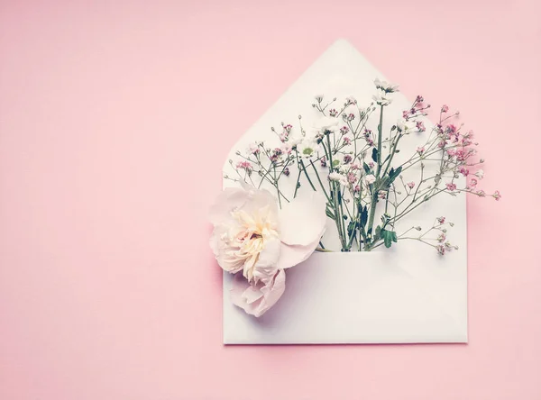 打开的信封 花朵排列在粉红的背景上 顶部视图 复制空间 富有创意的问候 邀请和假日概念 — 图库照片