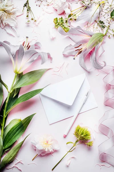 空白白色的信封与铅笔和各种装饰设备和花在粉红苍白的桌子背景 顶部视图 节日邀请 创意问候和假日 — 图库照片