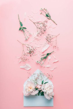 Üzerinde pastel çiçekler ve pembe soluk arka planda taç yaprakları olan açık bir zarf.