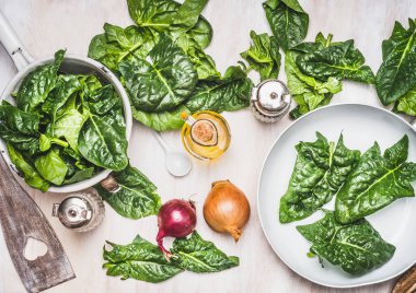 Beyaz arka planda ıspanak yaprakları, vejetaryen malzemeler ve mutfak aletleri, üst manzara. Sağlıklı beslenme ve pişirme, temiz veya diyet gıda konsepti