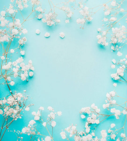 明るい青ターコイズの背景 トップビュー フレーム上の美しい白い小さな花 — ストック写真