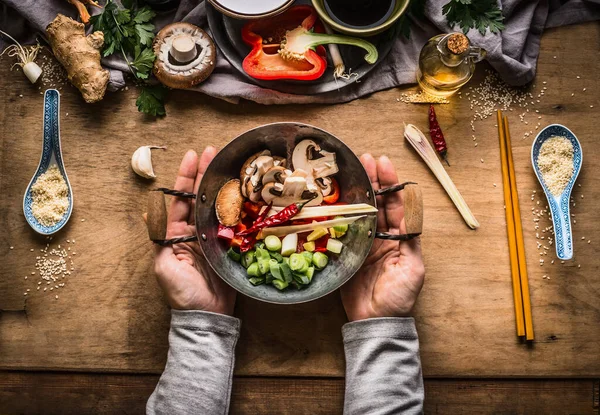 ベジタリアン炒め調理準備 女性の手は野菜の成分とキッチンテーブルの背景に炒め物のためのみじん切り野菜と小さな鍋を保持 トップビュー — ストック写真